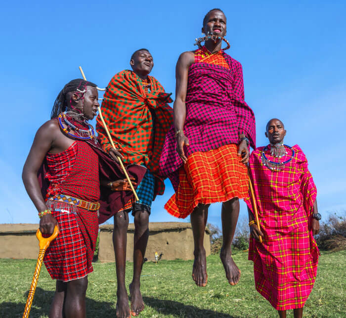 Maasai Mara man in traditional colorful clothing showing traditional Maasai jumping dance at Maasai Mara tribe village famous Safari travel destination near Maasai Mara National Reserve Kenya