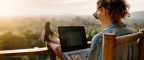 Woman sitting on a porch with her feet up on a laptop